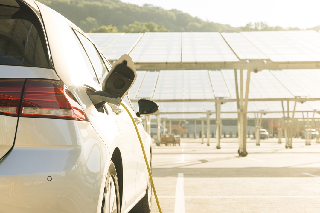 Auto lädt auf Parkplatz mit Solarpanelen